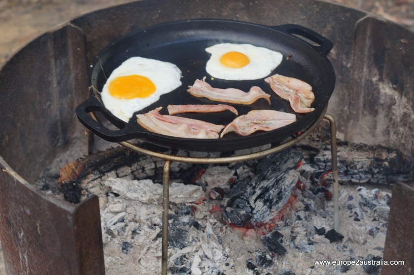 Put strips of bacon into the pan. Crack two eggs and place alongside. Season with salt and pepper to taste.
